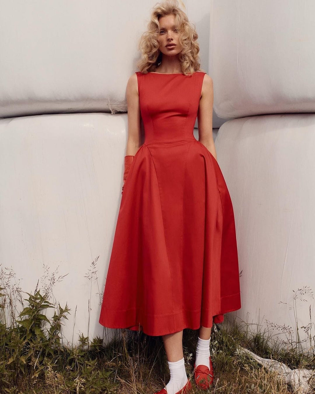 Woman wearing a red dress standing outdoors with a neutral background