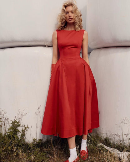 Woman wearing a red dress standing outdoors with a neutral background