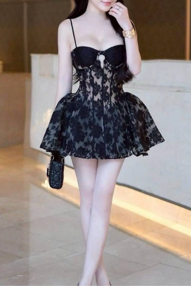 Woman in a black floral dress standing indoors with a blurred background