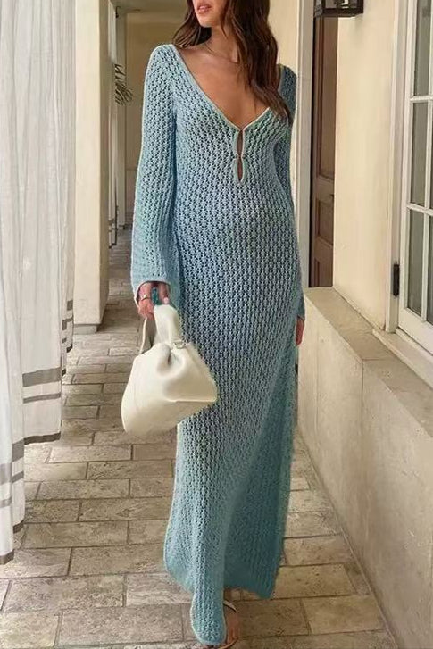 Woman in a light blue knitted dress holding a white handbag indoors.