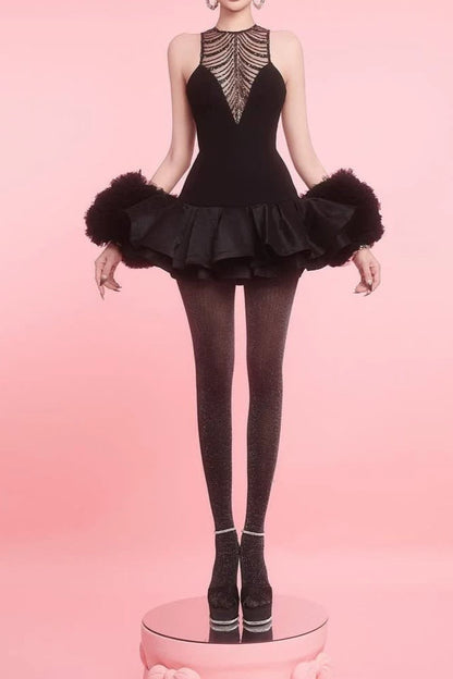 Model wearing a black dance costume with feathered sleeves on a pink background