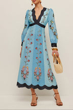 Woman wearing a blue embroidered dress with a plain background