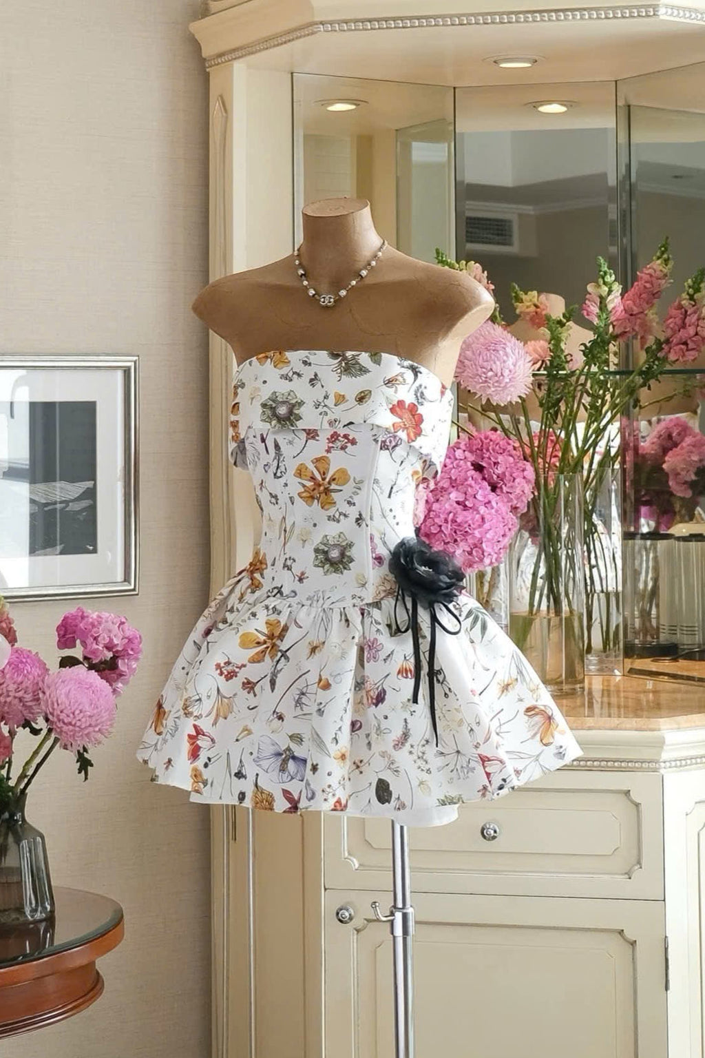 Floral dress on a mannequin in a room with flowers and furniture.