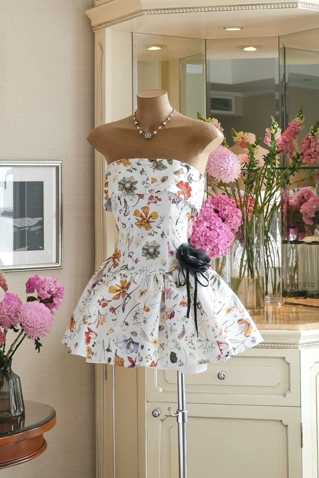 Floral dress on a mannequin in a room with flowers and furniture.