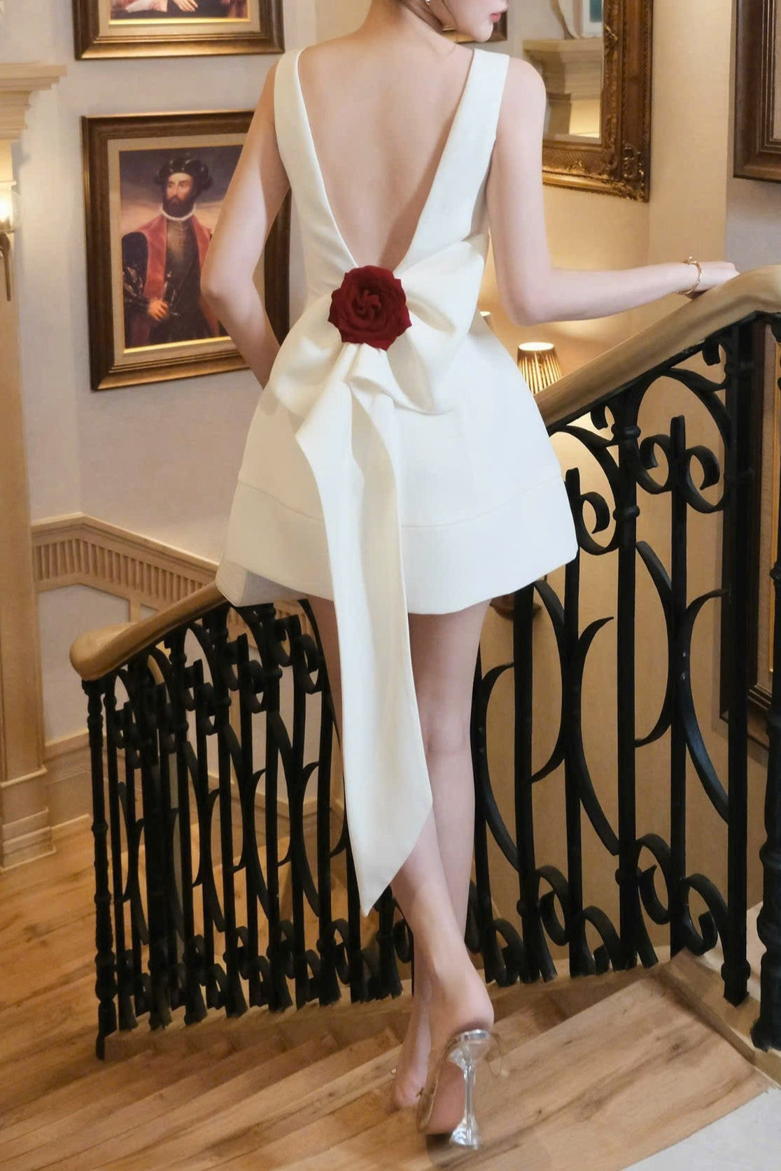 Woman in a white dress with a red flower standing in a staircase.