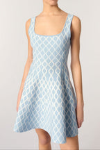 Woman wearing a light blue patterned dress on a plain background