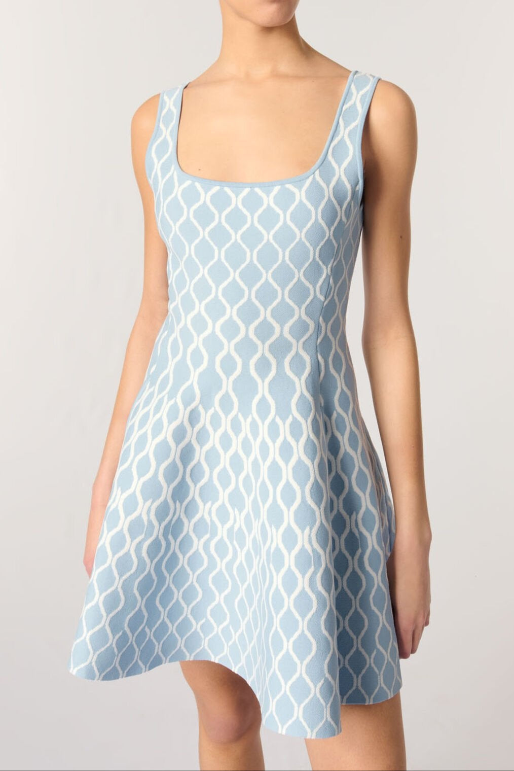 Woman wearing a light blue patterned dress on a plain background