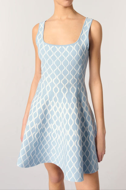 Woman wearing a light blue patterned dress on a plain background