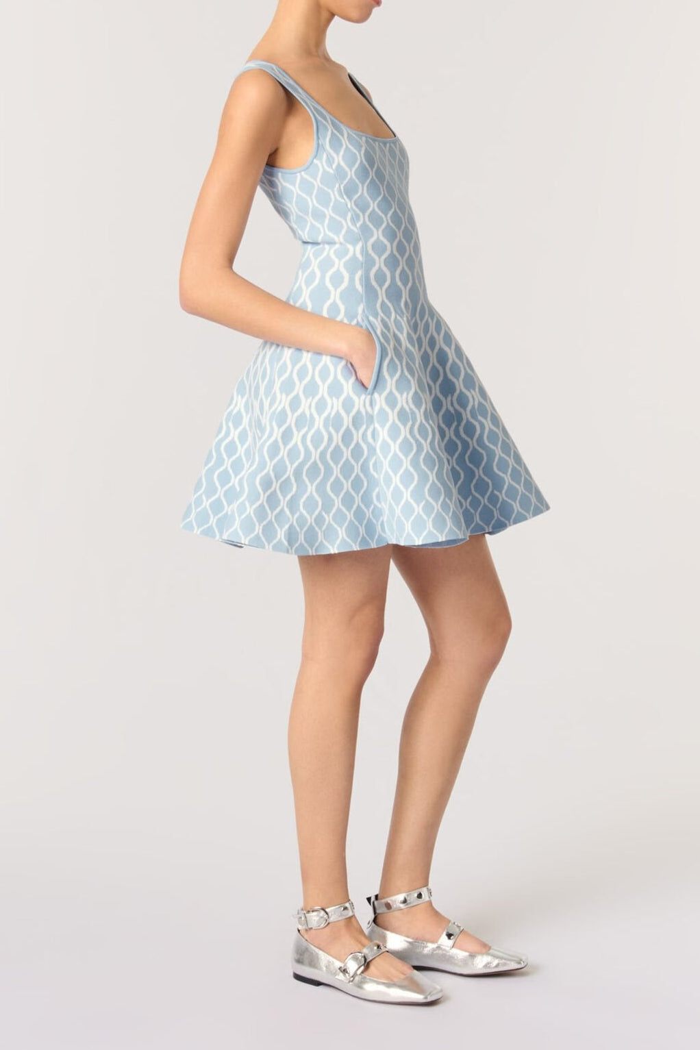 Woman wearing a light blue patterned dress on a white background