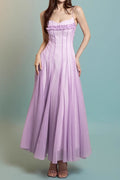 Woman wearing a long purple dress against a light blue background
