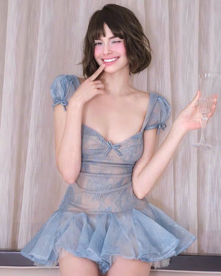 Woman wearing a blue lace dress against a neutral background