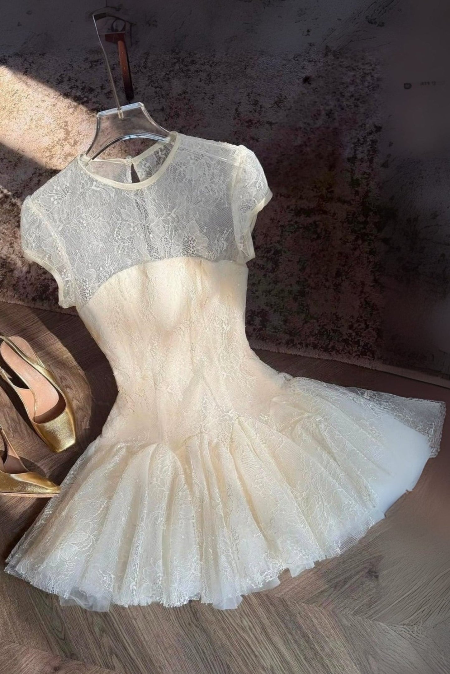 White lace dress with gold shoes on a textured surface