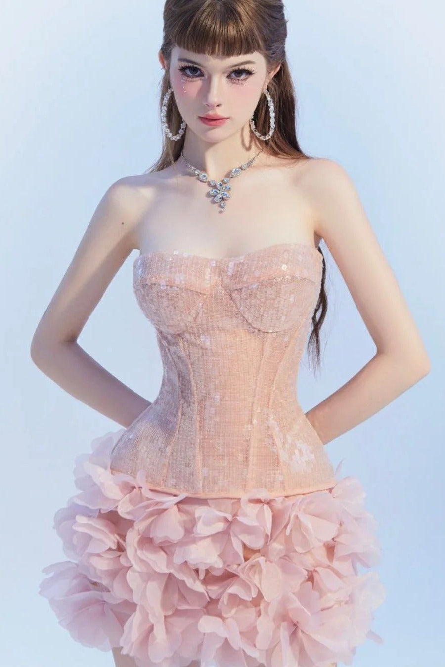 Woman wearing a pink strapless dress with a floral skirt against a light blue background