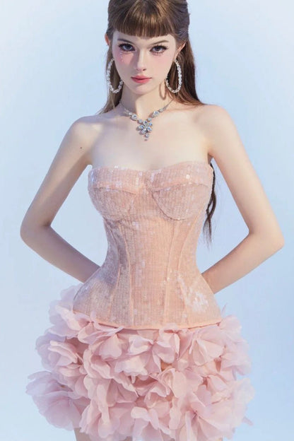 Woman wearing a pink strapless dress with a floral skirt against a light blue background