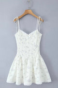 White lace dress on a wooden hanger against a gray background