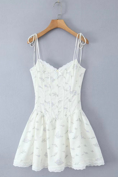 White lace dress on a wooden hanger against a gray background
